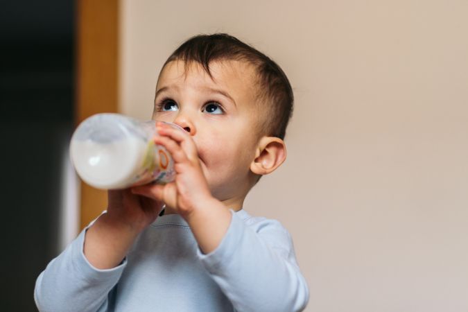 cute baby holding and drinking milk bottle