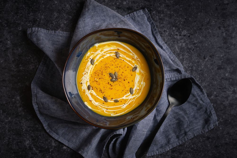 Bowl with pumpkin puree soup on table