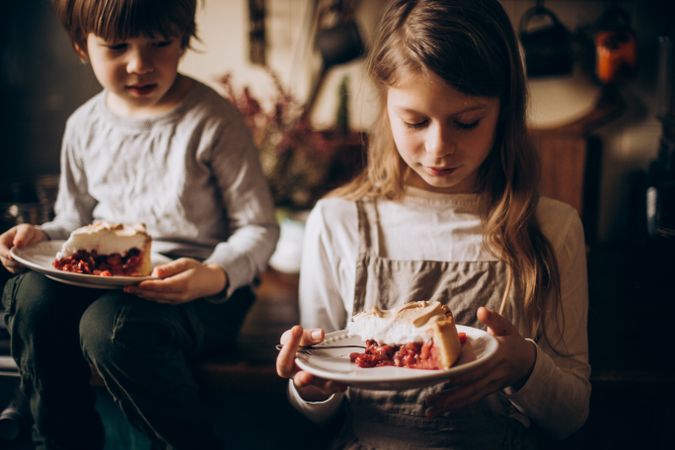Two kids eating cake slices on plate