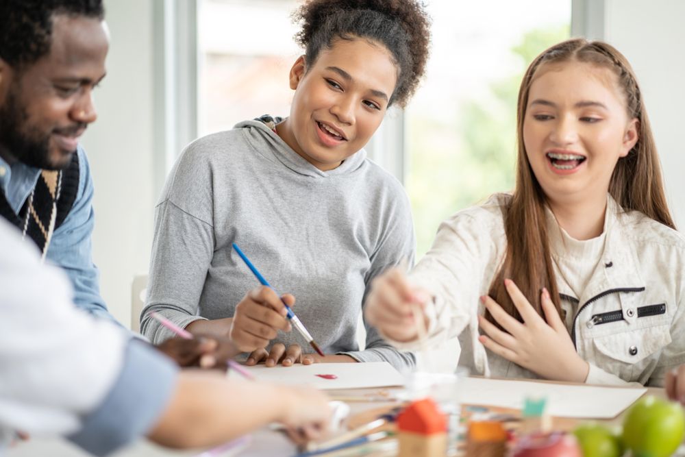 Smiling teenage students in painting class