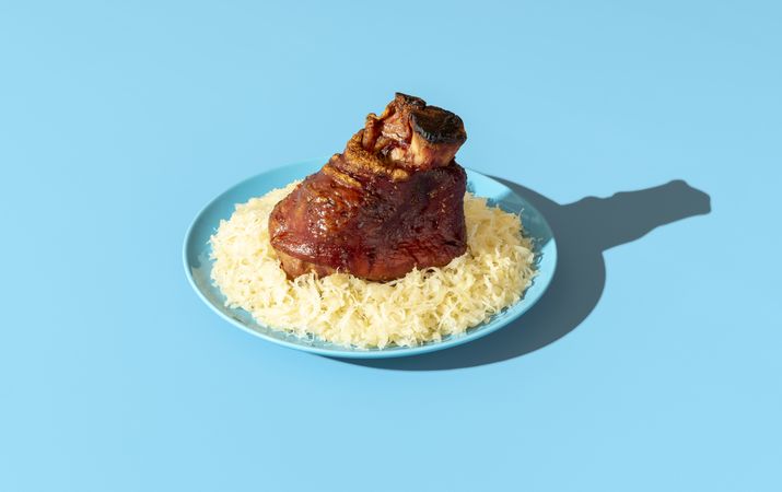 Roasted pork knuckle with sauerkraut minimalist on a blue table