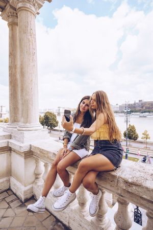 Laughing women taking selfie on old building