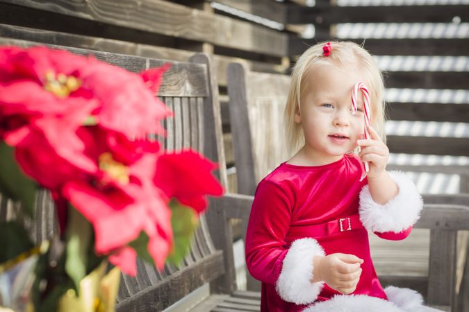 Adorable Little Girl Sitting On Bench with Her Candy Cane