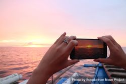 Woman holding smartphone shooting the sea during sunset 5k8WA4