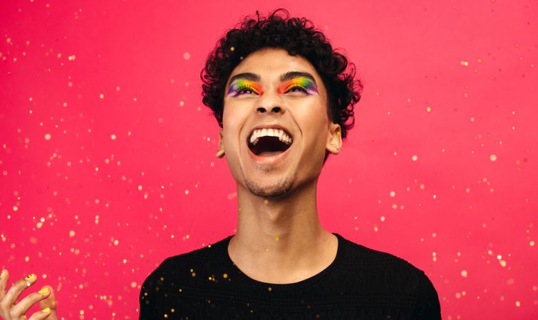 Cheerful man with glitters flying against red background