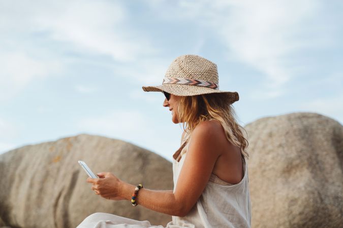 Contemporary woman with phone chilling on seashore
