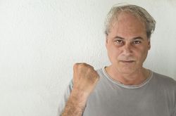Portrait of angry middle aged man in gray shirt holding a fist 5qKwwb