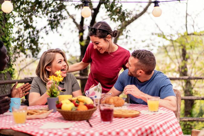 Group of diverse friends laughing and enjoying a picnic, sharing a moment of joy and casual dining