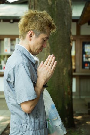 Side view of man in work suit praying