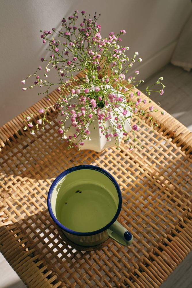 Cup of tea and blooming gypsophila on wicker table