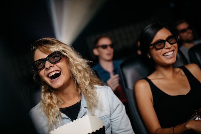 Female friends watching 3d movie and laughing in cinema