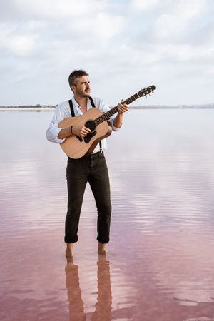 Inspired musician playing guitar at seaside