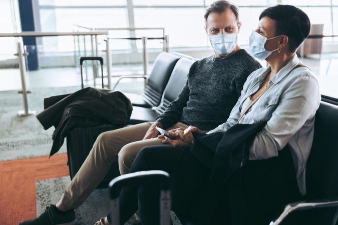Couple wearing face masks sitting at airport