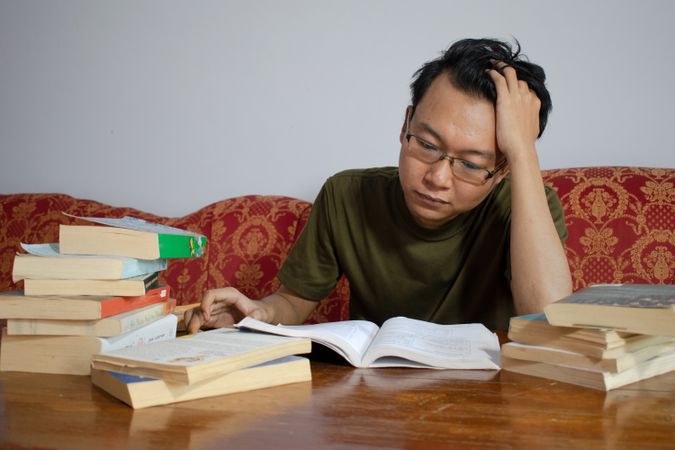 Asian young male reading book with frustrated gesture