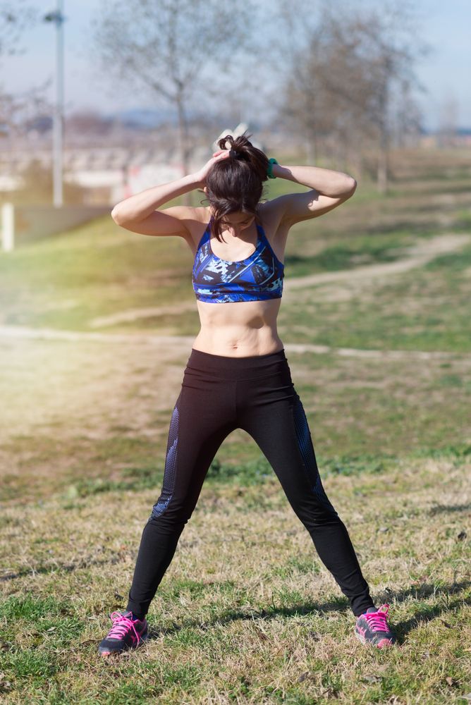 Fit woman stretching before workout in park