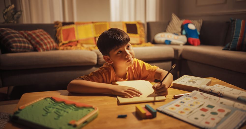 Evening Portrait of the Smart Young Boy Diligently Doing Homework in the Living Room.