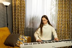 Girl in glasses playing piano with focus in decorated home.