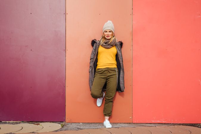 Blonde woman leaning on a colorful wall