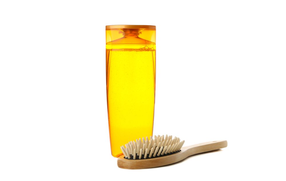 Blank shampoo bottle and hair brush isolated on light background