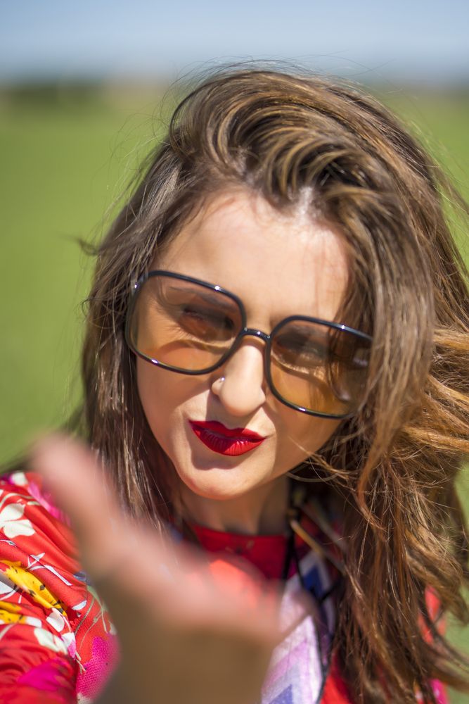 Cheerful woman in sunglasses looking at camera on sunny day
