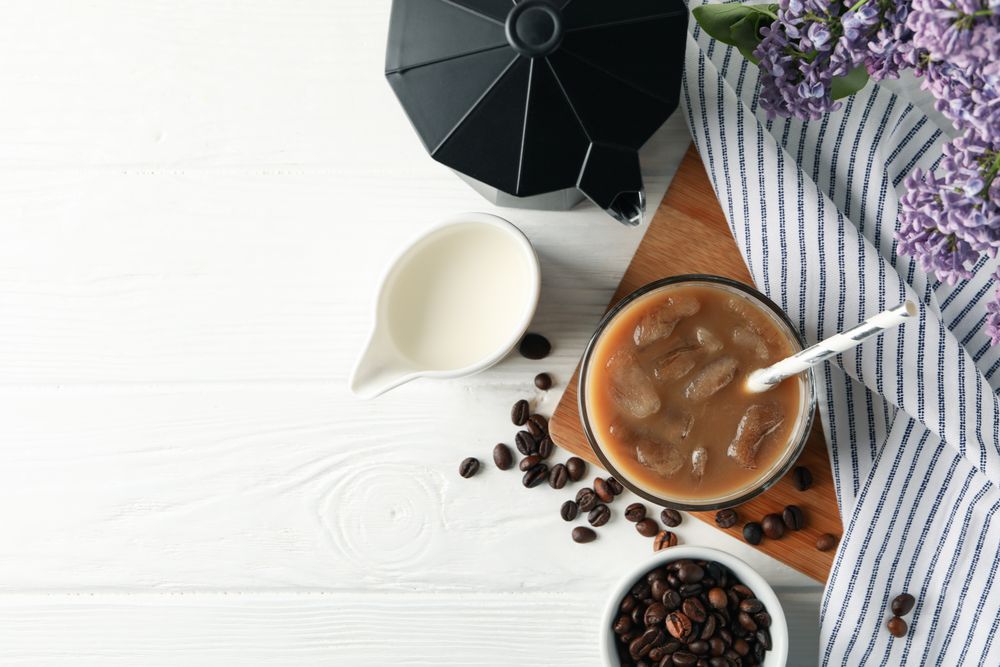 Composition with ice coffee and flowers on wooden background