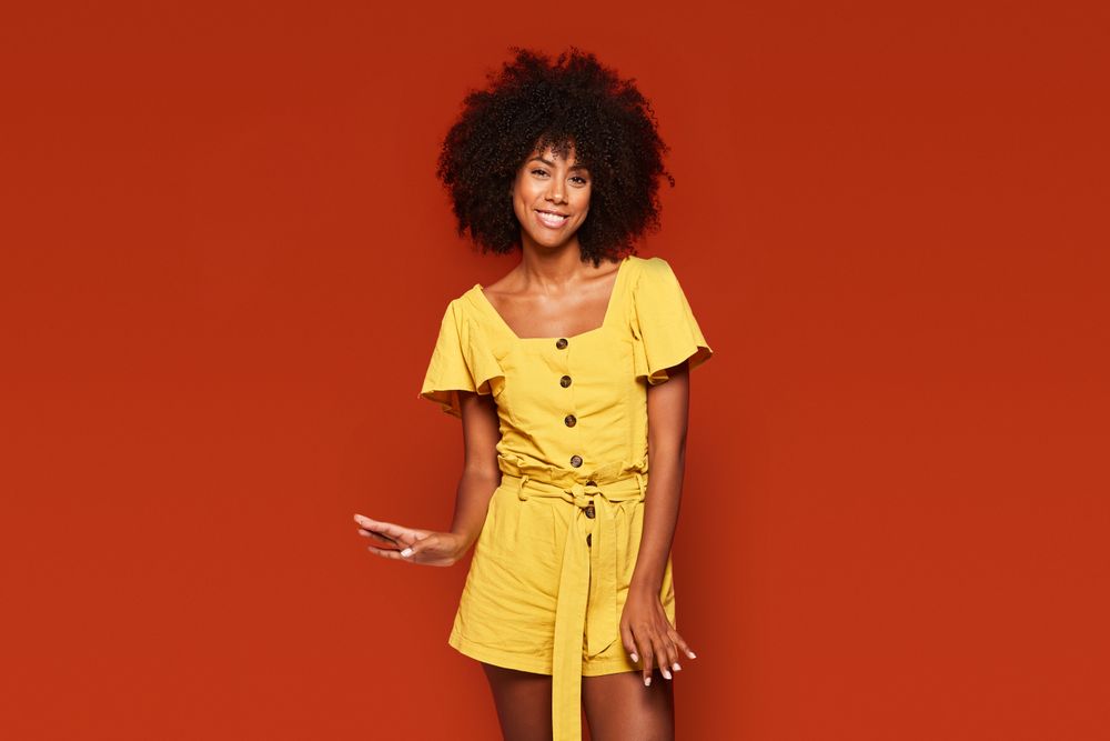 Bright Black woman in trendy dress smiling at camera