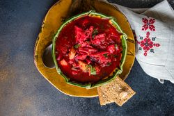 Top view Ukrainian beetroot soup borscht in green bowl with crackers