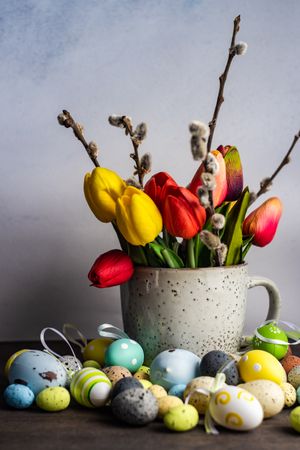 Easter card concept with eggs next to cup of tulips and pussy willow
