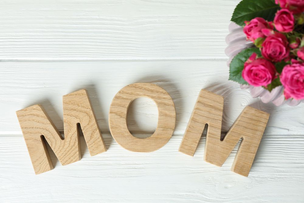 Composition with inscription Mom and pink roses on wooden background, top view