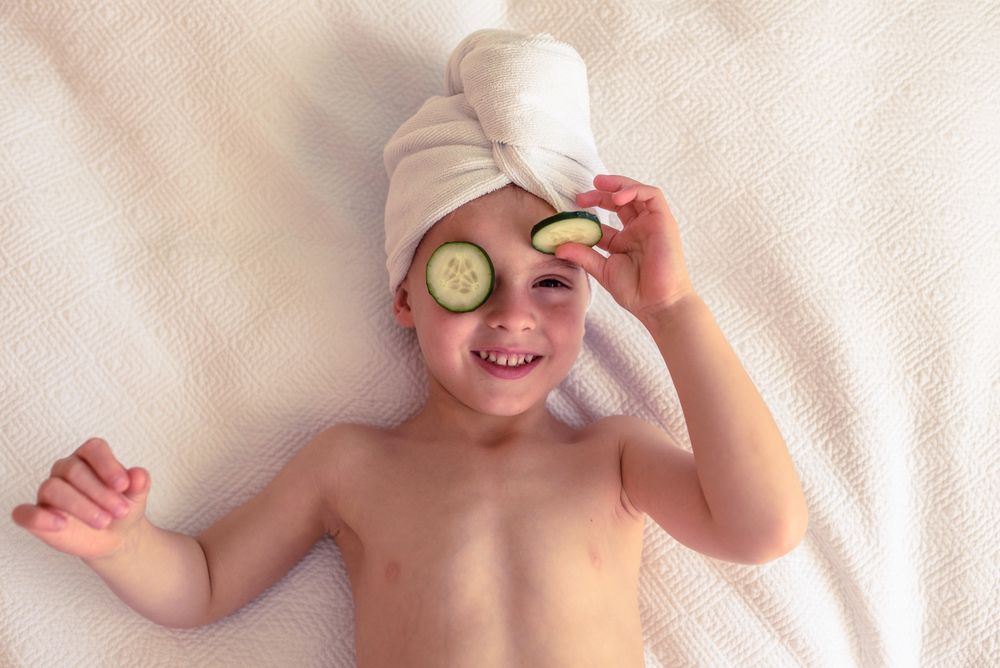 Cheerful boy with cucumber slices on eyes