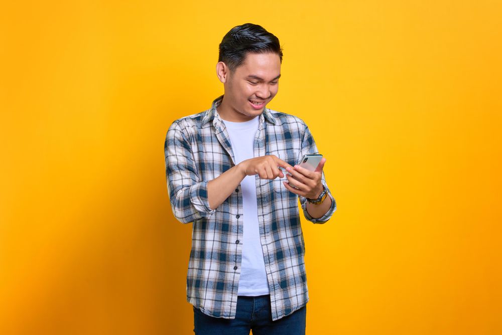 Smiling Asian male reading his phone