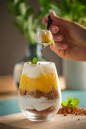 Crop woman with glass and spoon of cheesecake