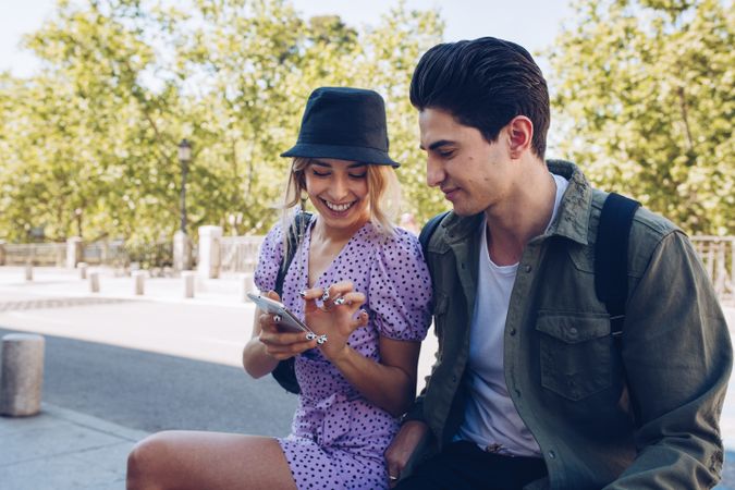 Happy young couple using phone in park