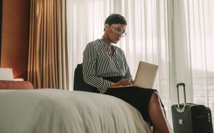 Businesswoman sitting on bed using laptop