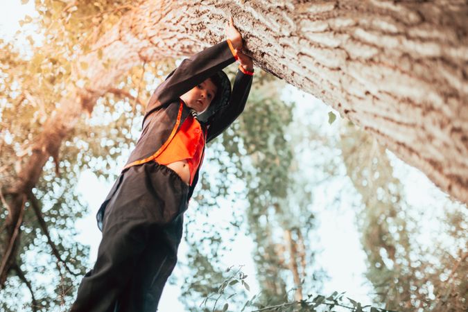 Boy leaning on tree in halloween costume