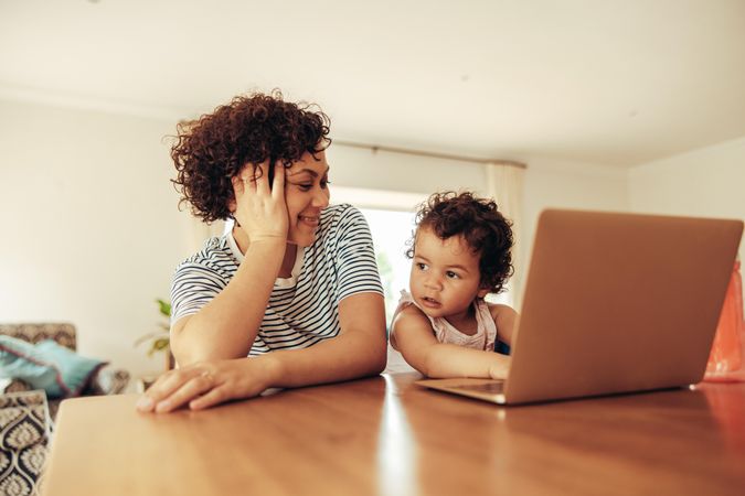 Happy mother and child sitting at table with a laptop
