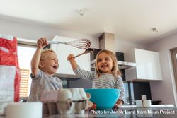 Cute little boy and girl play fighting with whisk and spatula while mixing batter in a bow 4BmEB5