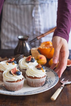Baker’s hands serving tasty carrot cupcakes on vintage dish