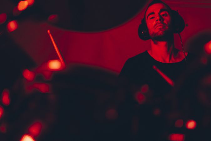 Man with drumsticks playing on drums in redness