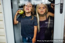 Two young girls pressing their nose against glass door bed8K4