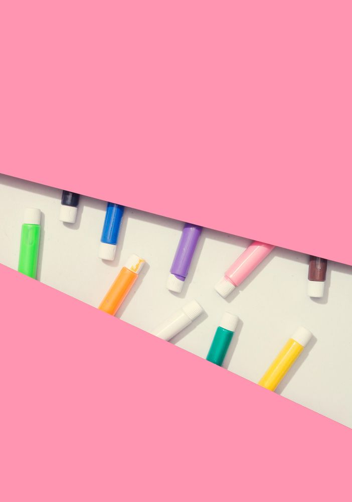 Pink paper with light geometric cut out and paint tubes