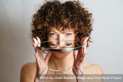 Woman holding mirror showing reflection of eyes beXgQA