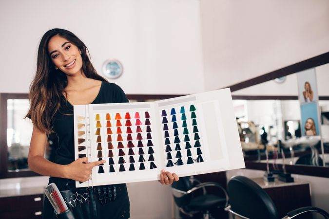 Professional colorist pointing at hair color sample chart