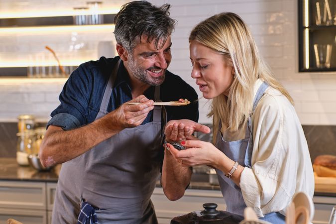 Husband feeding wife while cooking