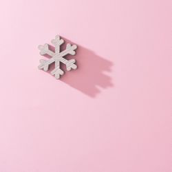 Wooden snowflake Christmas tree decoration with pink background with shadow