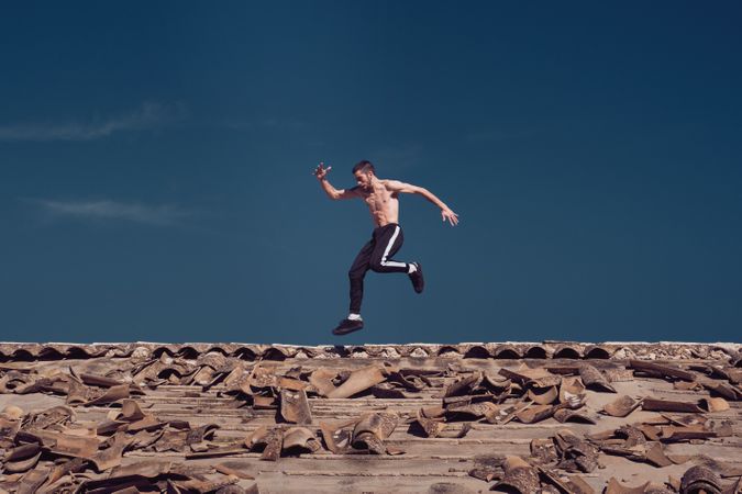 Active sportsman running and jumping on rooftop