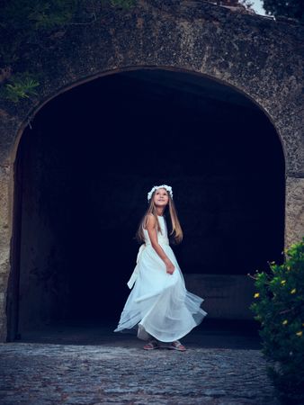 Elegant woman in elegant dress standing near arched wall entranc