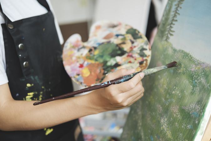 Young Asian female artist painting on canvas doing art projects on her studio.