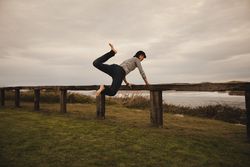Woman jumping near bench on shore near water