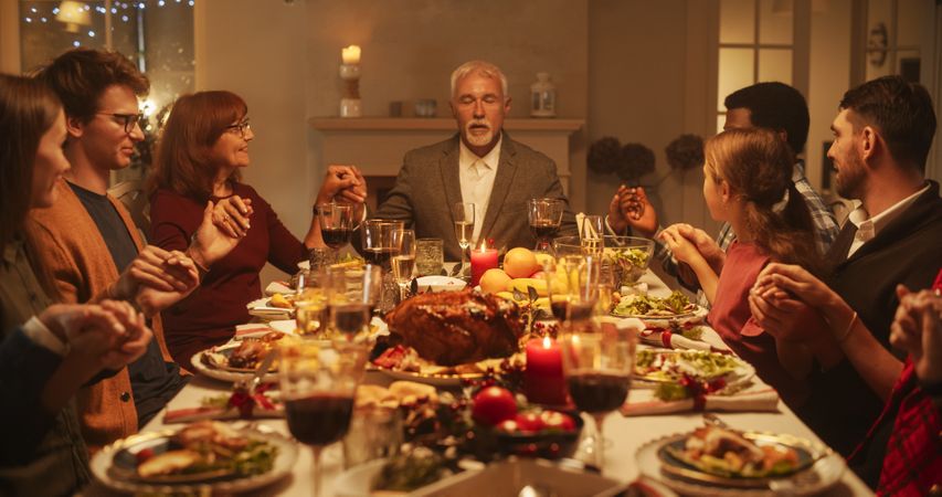 Religious Family Celebrating Christmas at Home. Relatives and Friends Praying and Holding Hands, Blessing Food Before Eating Dinner.
